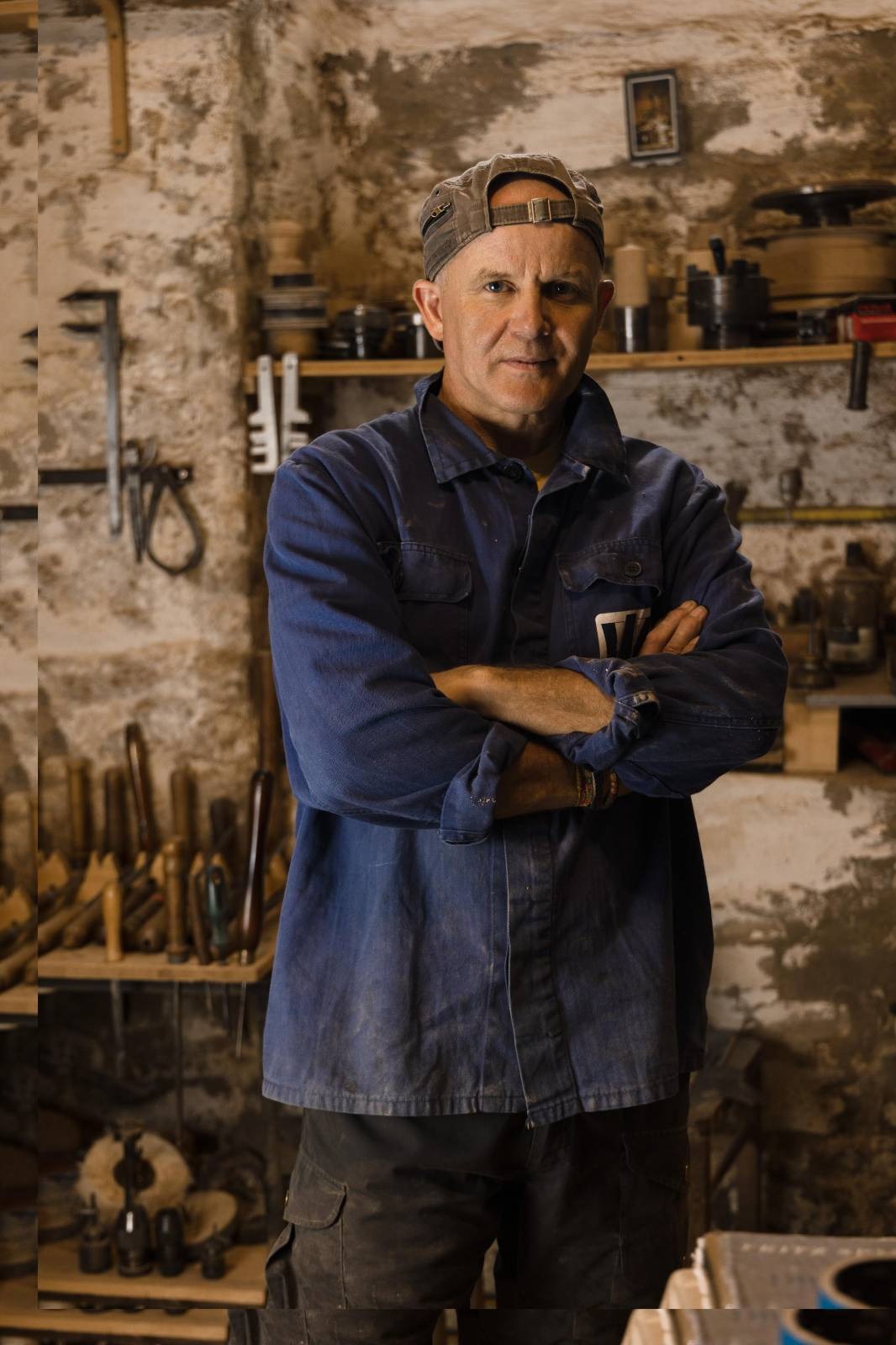 middle-aged handcraftsman standing in his atelier with crossed arms