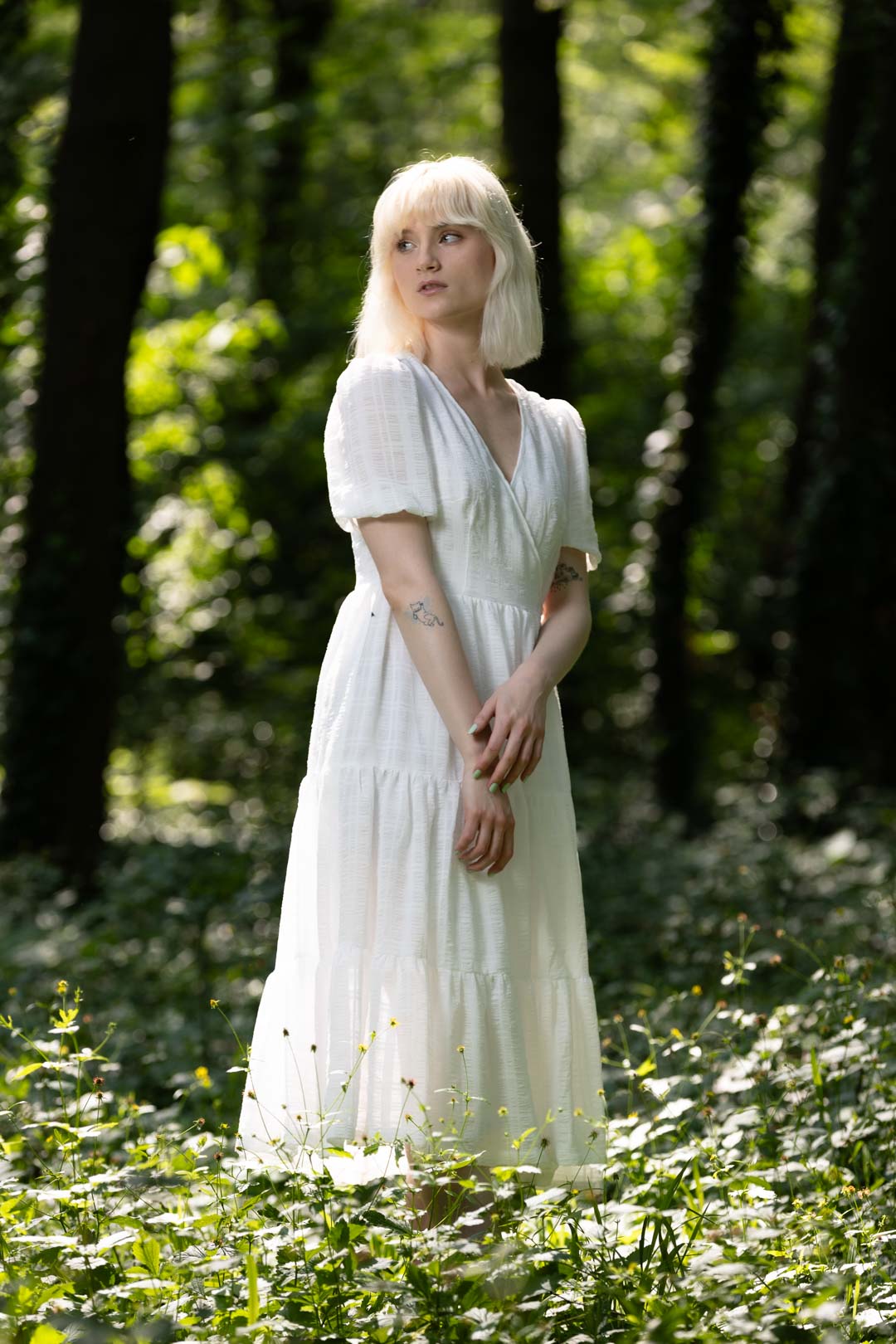 blondes weibliches Model in heller Waldlandschaft mit Blick zur Seite